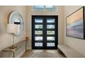 Entryway with modern door, round mirror, console table, artwork and bench at 8537 Pavia Way, Bradenton, FL 34202