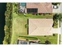 A bird's eye view of the home's tile roof, green lawn, and proximity to a body of water at 8772 Stone Harbour Loop, Bradenton, FL 34212