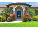 Arched entryway with vibrant blue door, flanked by lush, colorful landscaping at 1711 145Th E St, Sarasota, FL 34212