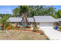 Charming single-story home showcasing stone accents, a well-manicured lawn, and lush landscaping with tropical palms at 2204 67Th W St, Bradenton, FL 34209