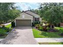 Attractive home featuring mature landscaping, brick paver driveway, and a welcoming facade at 5117 Serata Dr, Bradenton, FL 34211
