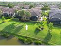 Aerial view of a home with a screened-in patio and a spacious backyard facing a pond at 5866 Cavano Dr, Sarasota, FL 34231