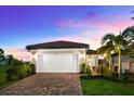 Charming home with a two-car garage and lush landscaping under a beautiful dusk sky at 6791 Alstead Cir, Bradenton, FL 34202