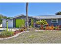 Charming home featuring a bright, lime-green garage door, landscaped garden, and a spacious driveway at 7355 Cass Cir, Sarasota, FL 34231