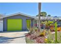 Home with bright green garage and front door, palm trees, landscaping, and a spacious driveway at 7355 Cass Cir, Sarasota, FL 34231