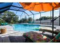 Enjoy this screened-in private pool area with lounge chairs and an umbrella perfect for relaxing at 831 Palmetto Ne Dr, Port Charlotte, FL 33952