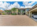 Exterior of a multi-Gathering home with attached garages and brick-paved driveway, lush landscaping at 13609 Messina Loop # 104, Bradenton, FL 34211