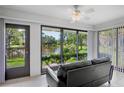 Bright sunroom with a peaceful pond view, tile floors, and a comfortable black couch at 3362 Sandleheath # 12, Sarasota, FL 34235