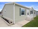 Angle view of the exterior with green siding and decorative brick planter at 3818 Chris Dr, Wesley Chapel, FL 33543