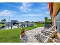 Scenic backyard featuring a paver patio, manicured lawn, and waterfront views with a boat dock at 3876 Catalina Dr, Bradenton, FL 34210