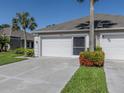 Single-story home with a two-car garage, complemented by beautiful tropical landscaping at 4153 Fairway Dr, North Port, FL 34287