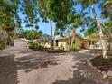 Expansive exterior view showcasing the home's layout with lush landscaping and a long driveway at 4830 Estrada De Costa, Sarasota, FL 34242