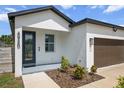 A modern home's front exterior boasts a dark-colored door, lush landscaping, and a two-car garage at 4920 69Th N St, St Petersburg, FL 33709