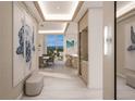 Elegant hallway with a large turtle artwork, wine fridge, recessed lighting, and an ocean view at the end at 555 Quay Cmn # 2004, Sarasota, FL 34236