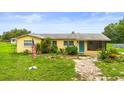 Charming yellow home features lush landscaping, vibrant blue door, and a welcoming screened porch at 5981 Jim Davis Rd, Parrish, FL 34219