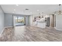 Bright, open-concept living area featuring wood-look flooring and sliding glass doors to the pool at 7442 N Leewynn Dr, Sarasota, FL 34240