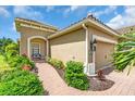 Home exterior featuring a two-car garage, neatly trimmed landscaping, and brick walkway to the front door at 1301 Backspin Dr, Englewood, FL 34223