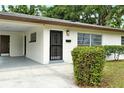 Close-up of the front of the house, highlighting the carport, decorative shrubs, and the secure, grilled front door at 1354 22Nd St, Sarasota, FL 34234