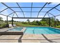 Relaxing screened-in pool area with a connected spa and a view of the open landscape at 15316 Shady Palms Ln, Nokomis, FL 34275