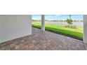 View of lake from the brick-paved, covered patio with white posts and bright green grass at 17333 Savory Mist Cir, Bradenton, FL 34211