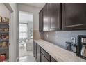 Butler's pantry featuring granite countertop, dark cabinets, grey backsplash and pantry shelves at 2136 Midnight Pearl Dr, Sarasota, FL 34240