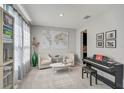 Bright living room with carpet, two chairs, a table, and a piano, complemented by a world map and curtains at 2136 Midnight Pearl Dr, Sarasota, FL 34240