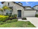 Elegant front entrance featuring a stone facade, well-manicured landscaping, and a lush green lawn at 3553 Secluded Ct, Sarasota, FL 34240