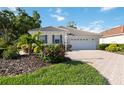 Inviting home with a tile roof, two-car garage, and a patterned paver driveway surrounded by lush landscaping at 5018 Hanging Moss Ln, Sarasota, FL 34238