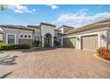 Beautiful home exterior showcasing a three-car garage, and lush landscaping with a paver driveway at 5328 Brookgrove Dr, Sarasota, FL 34238