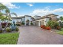 Beautiful home exterior showcasing a three-car garage, and lush landscaping with a paver driveway at 5328 Brookgrove Dr, Sarasota, FL 34238