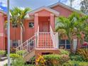 Inviting coral condo featuring a landscaped entrance with stairs leading to the front door at 5500 Longwood Run Blvd # 203, Sarasota, FL 34243