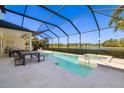 A stunning screened-in pool and spa area with travertine pavers and views of a serene lake at 826 Honeyflower Loop, Bradenton, FL 34212