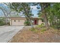 Modest exterior of single Gathering home featuring an attached garage and mature trees in the yard at 9300 Gulf Blvd, St Pete Beach, FL 33706