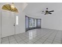 Bright foyer featuring white tile flooring, a decorative ceiling fan, and a stylish front door at 1026 Graham Rd, Venice, FL 34293