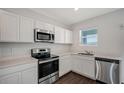 Well-equipped kitchen boasts stainless steel appliances, white cabinetry, and ample counter space for meal preparation at 13136 Bayberry Way, Parrish, FL 34219