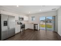 Modern kitchen featuring stainless steel appliances, white cabinets, and a sliding glass door for natural light at 13136 Bayberry Way, Parrish, FL 34219