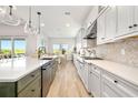 Modern kitchen features bright white cabinetry, stainless appliances, a large island, and a view to the outdoors at 17128 Ranchside Pl, Lakewood Ranch, FL 34211