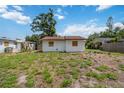 View of back of home with boarded up windows, overgrown lawn, and exterior siding at 2558 Hawthorne St, Sarasota, FL 34239