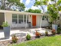 Close-up of the front porch with an orange door, potted plants, and a small seating area at 2933 Michigan St, Sarasota, FL 34237