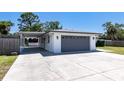 Side view of the home showing a carport, garage, and concrete driveway, with a tidy green lawn at 3338 Roslyn Rd, Venice, FL 34293