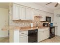 Well-lit kitchen features white cabinets, tiled backsplash, black appliances, and a peninsula counter at 4165 66Th Street W Cir # H, Bradenton, FL 34209