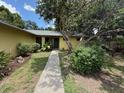 Quaint single-story home with mature landscaping, lush green bushes, and a welcoming walkway to the front door at 5032 81St Avenue E Ter, Sarasota, FL 34243
