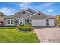 Attractive single-story home featuring a well-kept lawn, brick driveway, and blooming flower beds at 5515 69Th E Pl, Ellenton, FL 34222