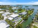 Aerial view of the contemporary waterfront home with a pool, dock, and lush landscaping in the community at 590 De Narvaez Dr, Longboat Key, FL 34228