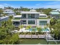 Modern home features a private pool, a lush outdoor area, and a boat dock on the water at 590 De Narvaez Dr, Longboat Key, FL 34228