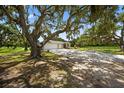 A ranch-style home with a well-manicured lawn and mature trees provides ample shade and curb appeal at 6875 Myakka Valley Trl, Sarasota, FL 34241