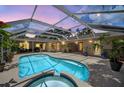 An enclosed backyard pool with a connected hot tub surrounded by lush plants and comfortable outdoor furniture at 6875 Myakka Valley Trl, Sarasota, FL 34241