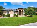 Charming one-story home with manicured lawn and covered entrance, complemented by lush landscaping and mature trees at 8312 Misty Lake Cir, Sarasota, FL 34241