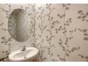 Stylish powder room featuring a round mirror and unique wallpaper at 8557 Milestone Dr, Sarasota, FL 34238