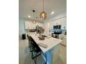 Modern kitchen with white cabinets, quartz countertops, stainless steel appliances, and pendant lighting at 11613 Woodleaf Dr, Lakewood Ranch, FL 34211